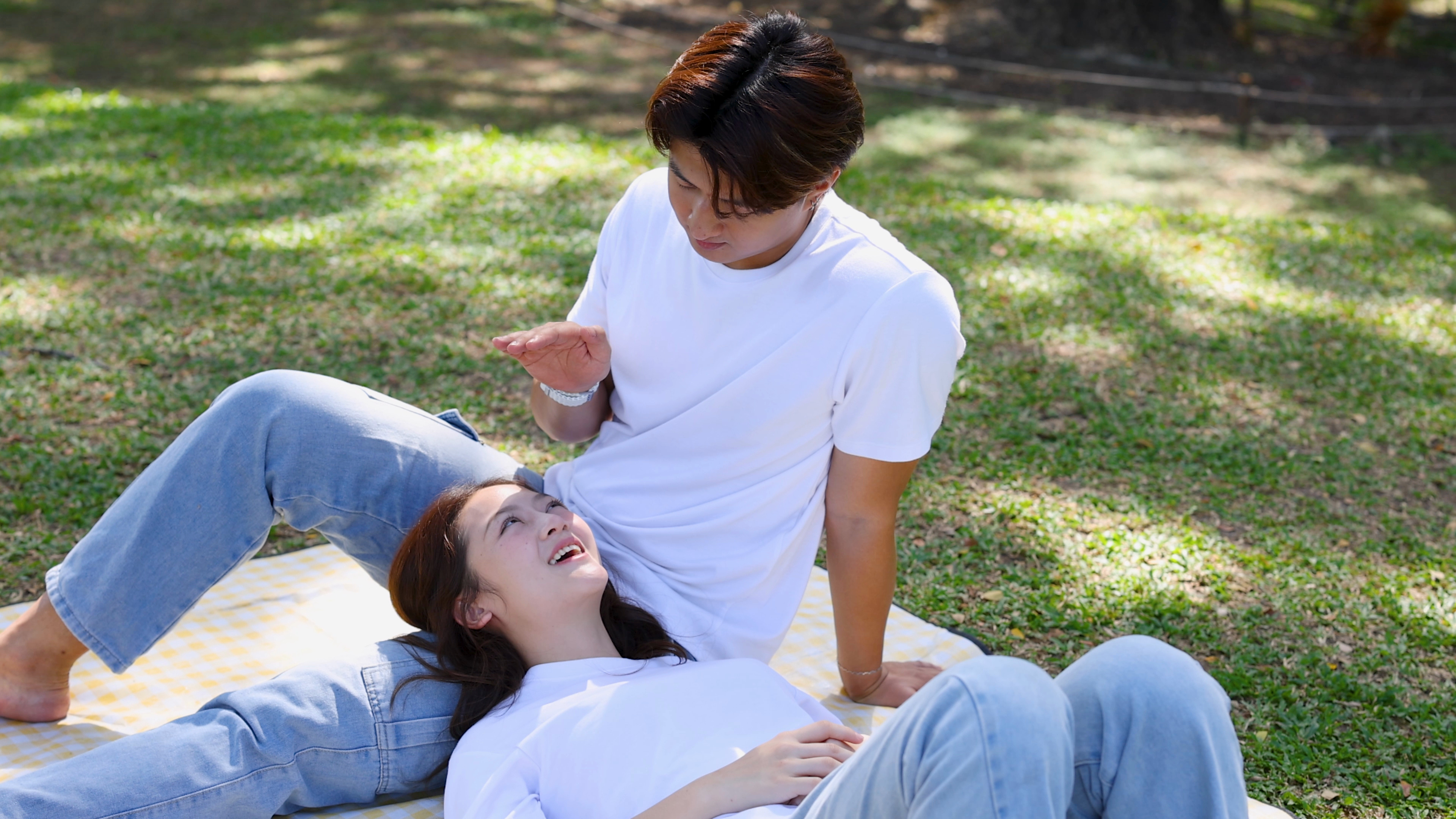 Couple relaxing on a picnic blanket in a sunny park